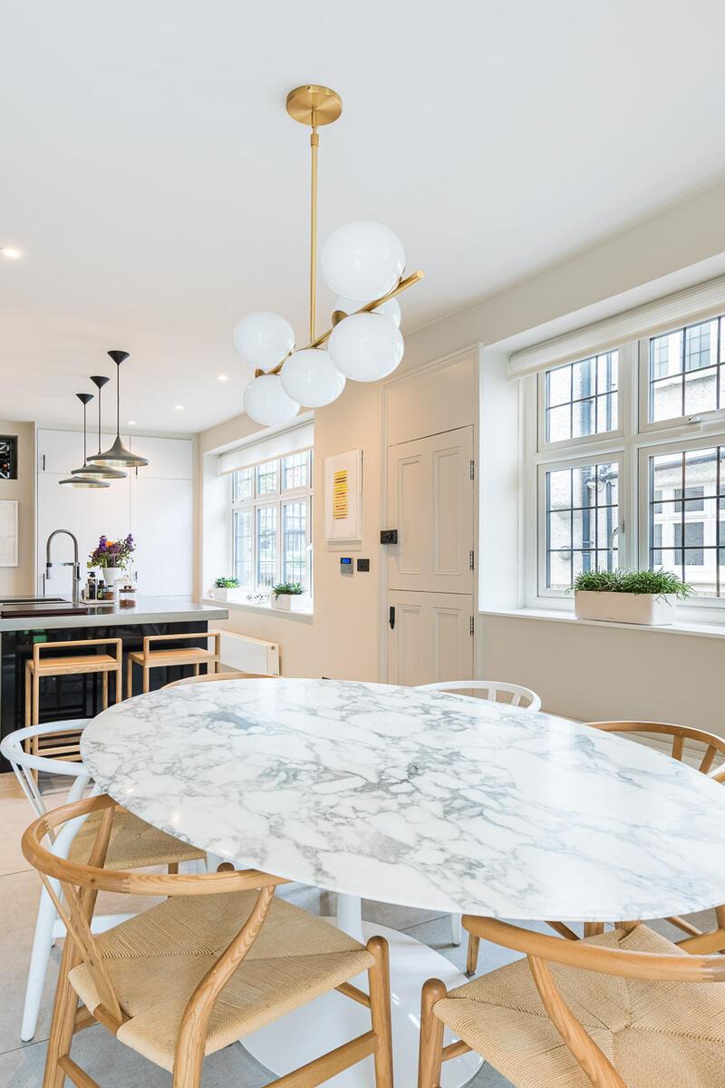 Modern kitchen and dining area with marble table, globe pendant lighting and large windows in North West London Arts & Crafts house.