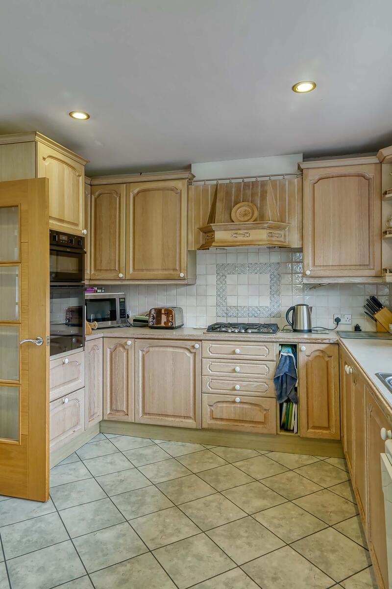 Traditional kitchen with light wood cabinets, tiled floor, double oven and large window overlooking the garden.