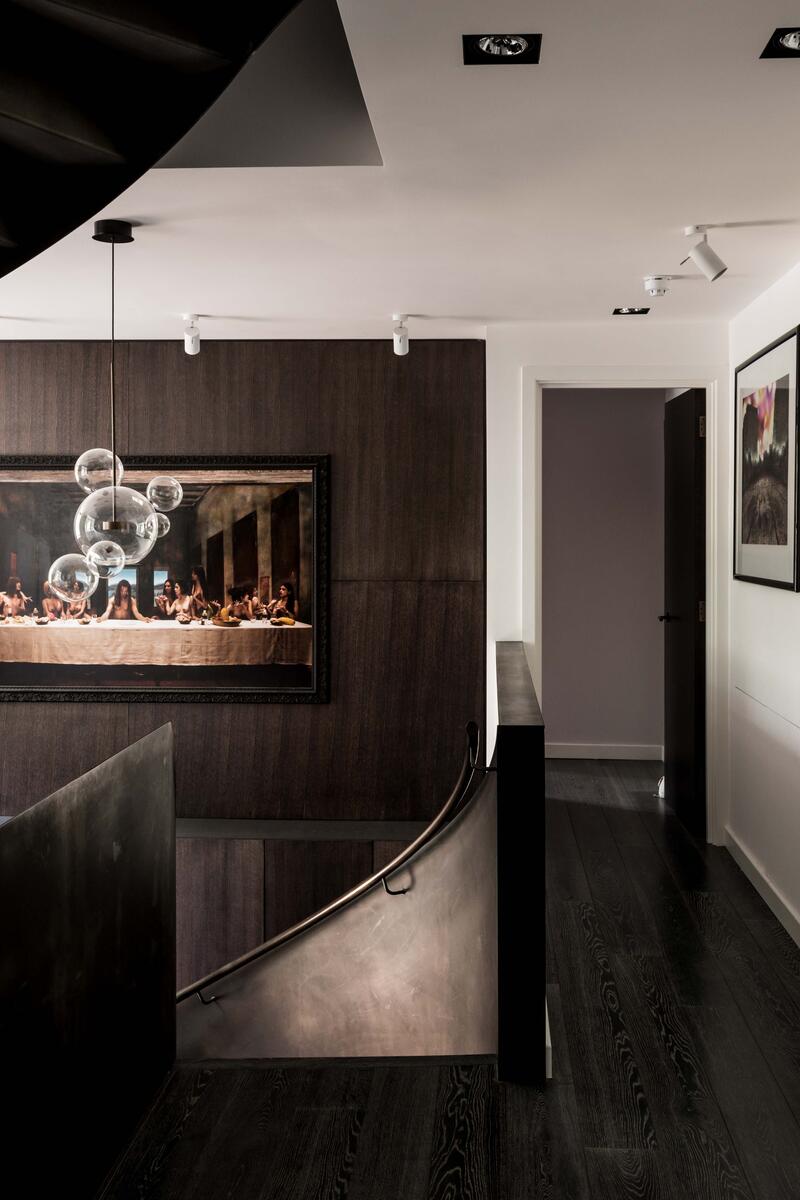 Modern landing with dark wood panelling, sculptural bubble pendant lights and a curved staircase in a luxury London house