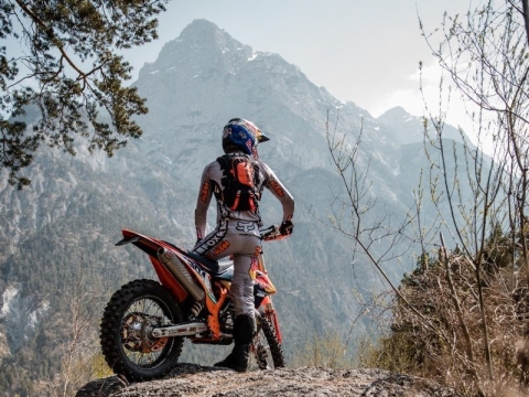 Man riding an offroad motorbike in the mountains showing a hydration pack
