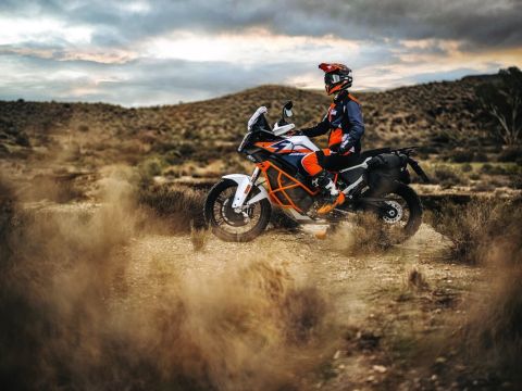 Adventure style motorbike stationery with rider say on it in a desert or scrubland environment