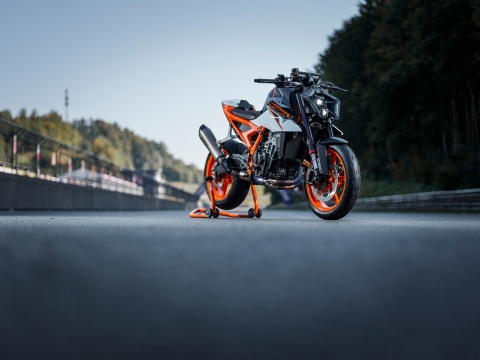 A low angle, atmospheric shot of a white, black and orange motorcycle on a stand in the middle of a race track.