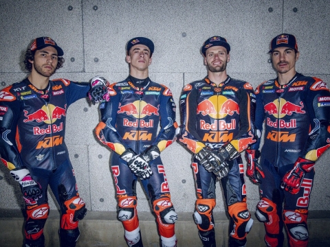 Red Bull KTM Riders Acosta, Binder, Bastianini and Vinales in a Moto GP 2026 group photo representing Red Bull KTM Factory Racing and Red Bull KTM Tech3. Wearing leather race suits and stood in front of a concrete wall.