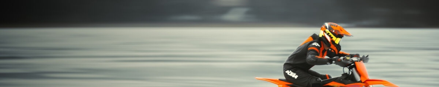 Motorcyclist racing an offroad bike wearing KTM race gear and goggles