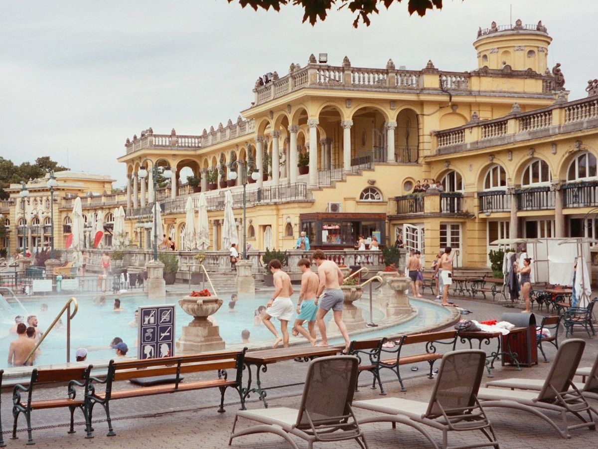 Three lads walking beside the steaming outdoor pool at Sz&eacute;chenyi Thermal Baths in Budapest