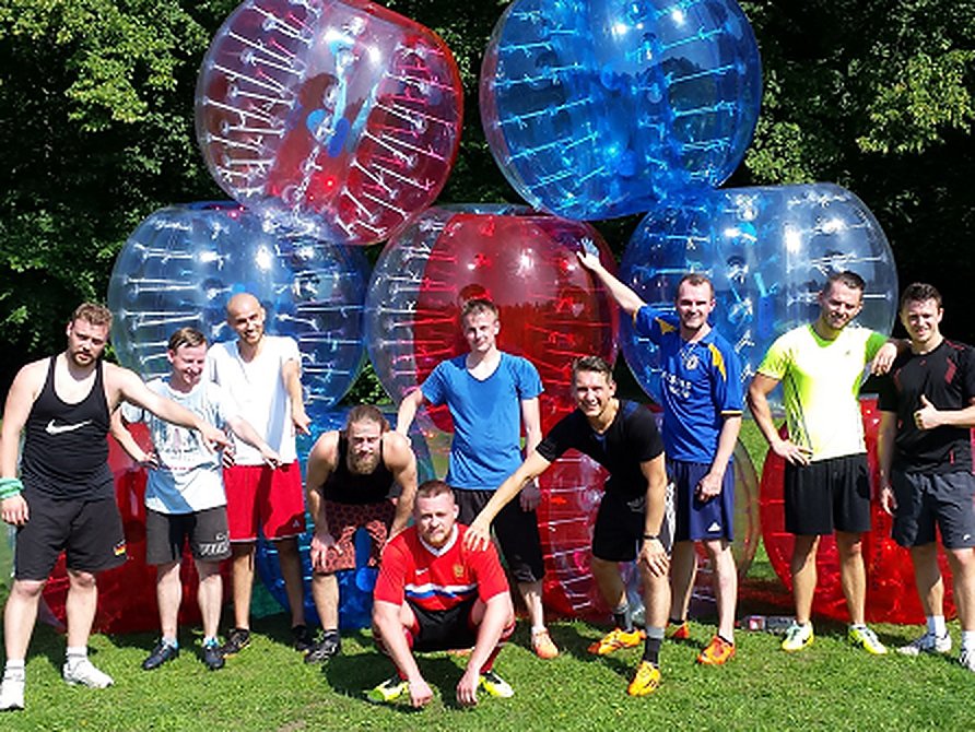 Stag group of nine lads posing in front of a stack of inflatable bubble football balls on a sunny day