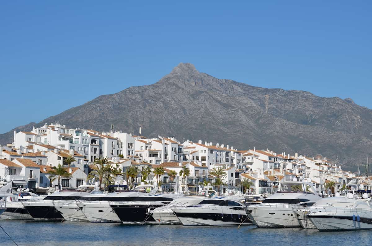 Luxury yachts moored in Puerto Ban&uacute;s marina with the whitewashed marina village and La Concha mountain behind