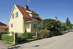 Tvåplansvilla med gult träfasad och tegeltak i bostadsområde