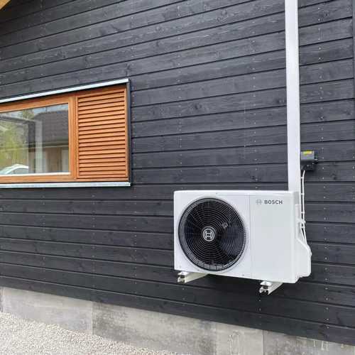 Luftvärmepump monterad på svart fasad