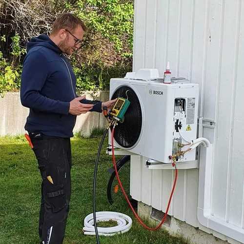 Bild på installatör som mäter av luftvärmepump