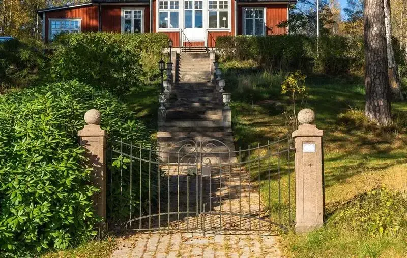 fin stigande trapp med grindstolpar i granit och ett rött hus