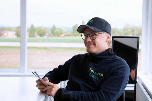 Medarbetare från Isolerab sitter på kontor med mobiltelefon, klädd i företagskläder