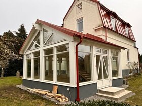 Inglasat uterum med rött tak på äldre villa