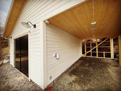 Laddbox och utebelysning monterade under taket på en carport