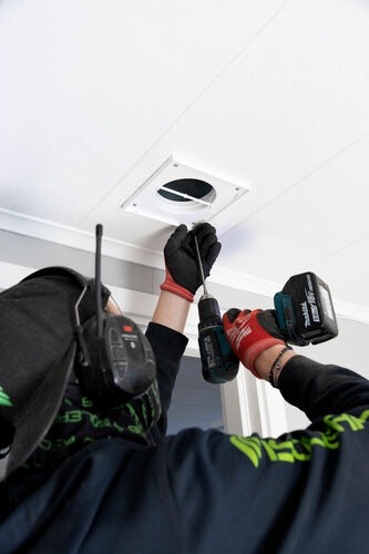 Ventilationstekniker skruvar fast ventilationsdon i tak vid inomhusinstallation