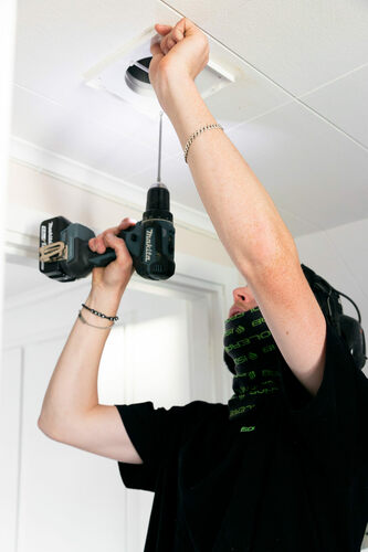 Installatör från Isolerab monterar ventilationsdon i innertak med skruvdragare