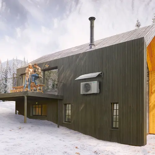 Svart luftvärmepump installerad i ljus matsal med vinterutsikt och par som njuter av varm dryck