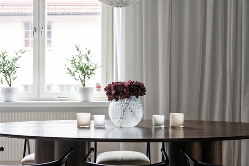 Matplats med mörkt bord och blommor vid fönstret intill ett kök i mörkt trä i Enskede, renoverat av Jobryan