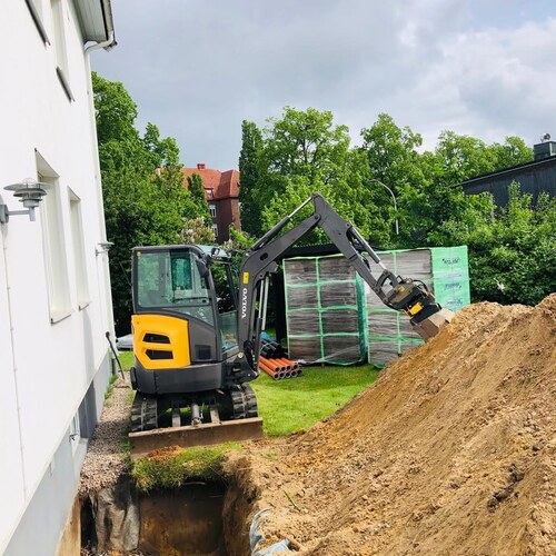 Grävmaskin vid villa i arbete med att gräva dräneringsschakt i Halland