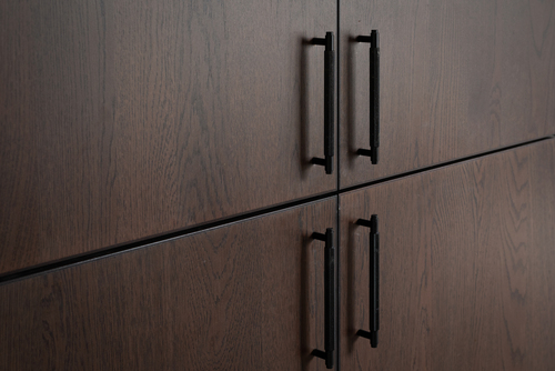 Närbild på mörka köksluckor med svarta handtag i modern stil