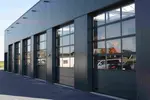 Industriportar med glaspartier på en kommersiell fastighet i grå plåtfasad