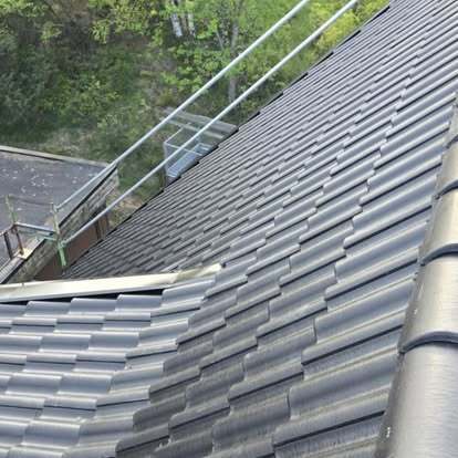 Svart tak med nylagda betongpannor och säkerhetsräcke – projekt av Takgruppen Sverige AB.