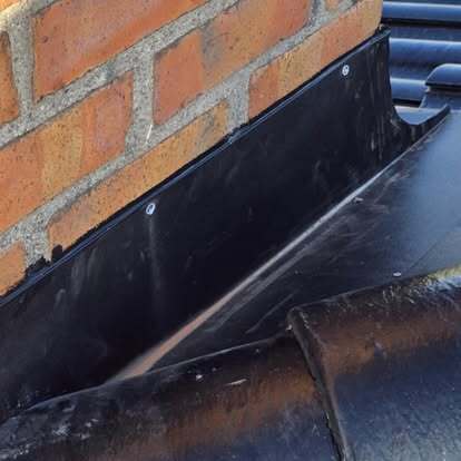 Plåtarbete vid skorsten på svart tak – tätning monterad av Takgruppen Sverige AB.