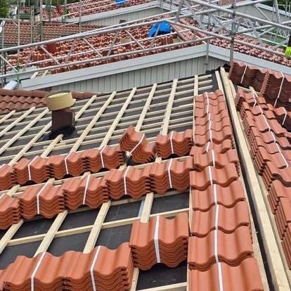 Pågående takläggning med röda tegelpannor och synlig läkt – projekt av Takgruppen Sverige AB.