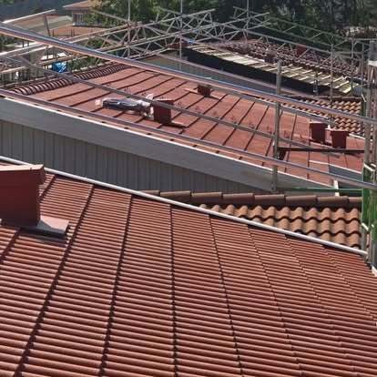 Röda tegeltak med byggställningar under pågående takarbete – projekt av Takgruppen Sverige AB.