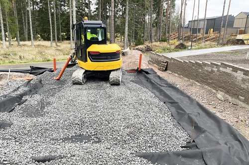 Grävmaskin som lägger grus