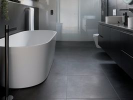Designbadrum i Gävle med fristående badkar, vägghängd toalett och mörka klinkers – stilren badrumsrenovering av LA Rörsystem AB.