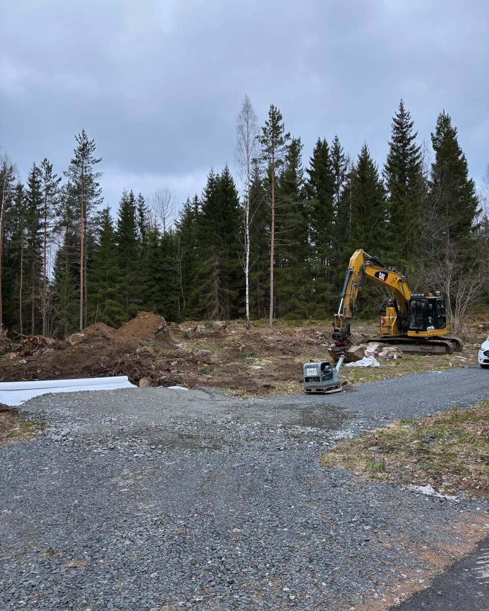Grävmaskin i arbete vid nybyggnation i skogsmiljö – schaktning och markförberedelse i Uppsala