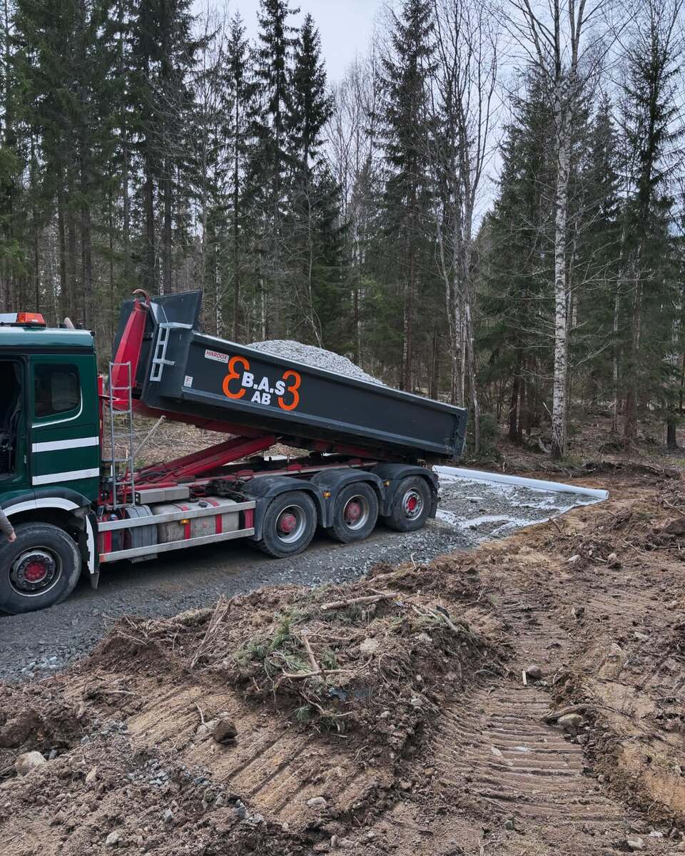 Tung lastbil från 3BAS AB tippas med grus vid skogstomt – leverans av fyllnadsmaterial i Norrtälje