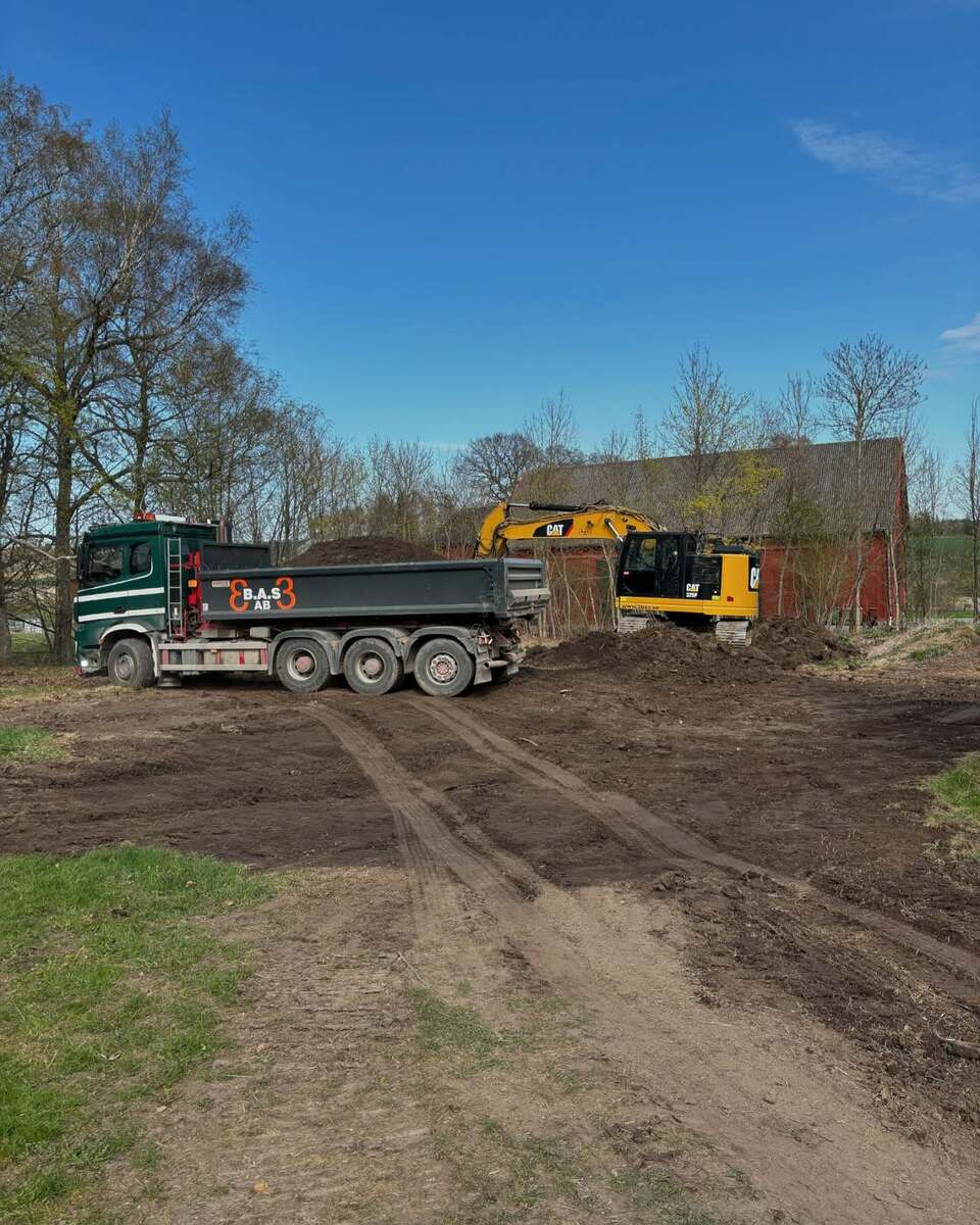 Lastbil och grävmaskin i samverkan vid tomtplanering – jordleverans och schakt i Stockholm