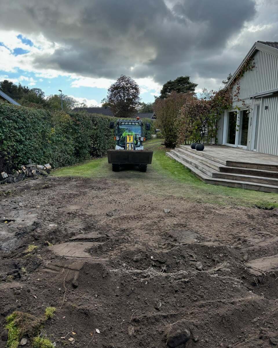 Trädgårdsarbete med grävmaskin framför villa – tomtplanering och markarbete i Norrtälje