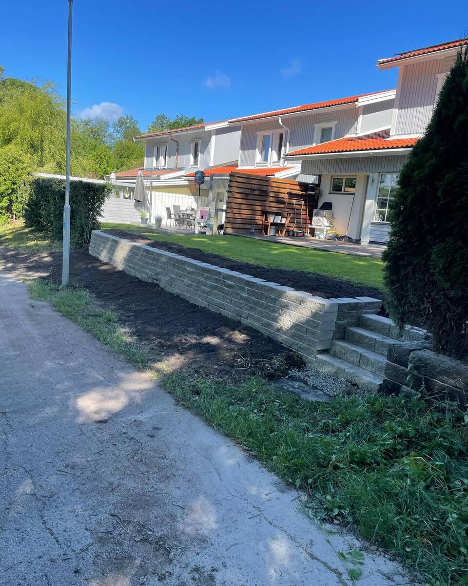 Färdigställd trädgård med stödmur och gräsmatta vid radhus – finplanering i Vallentuna