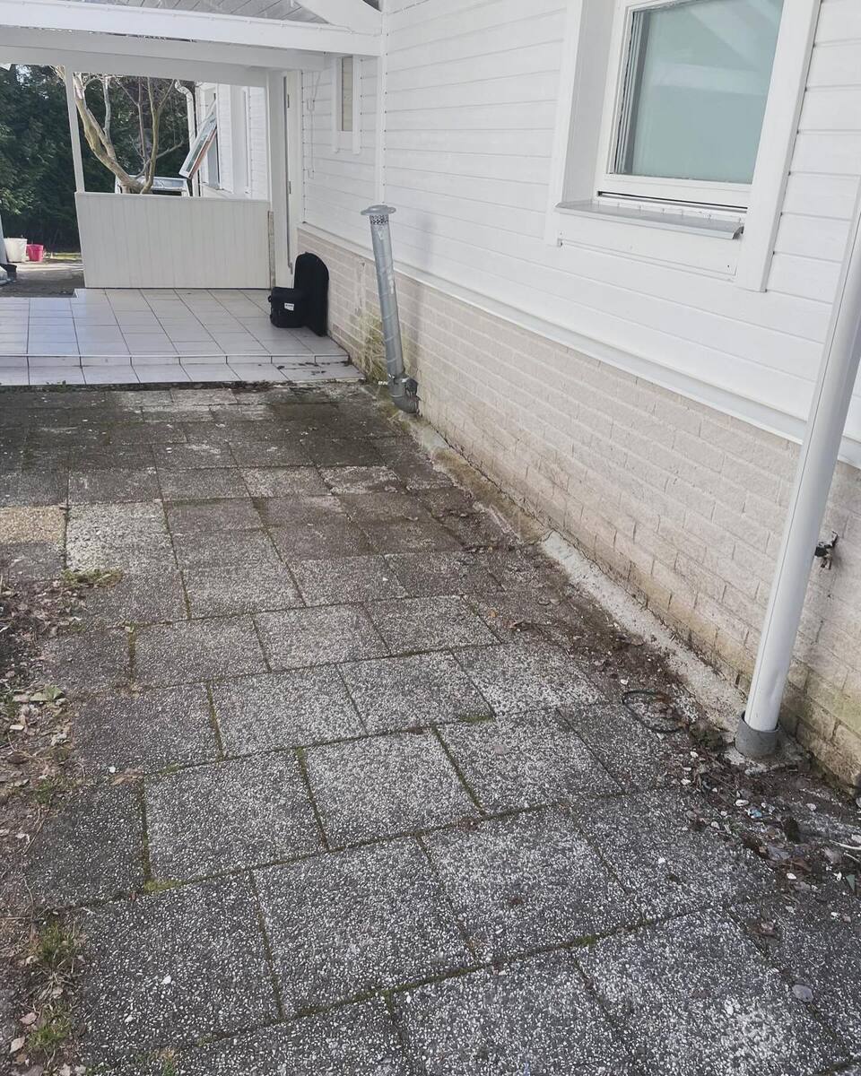 Äldre stensättning vid husfasad – behov av markrenovering och ny plattläggning i Norrtälje