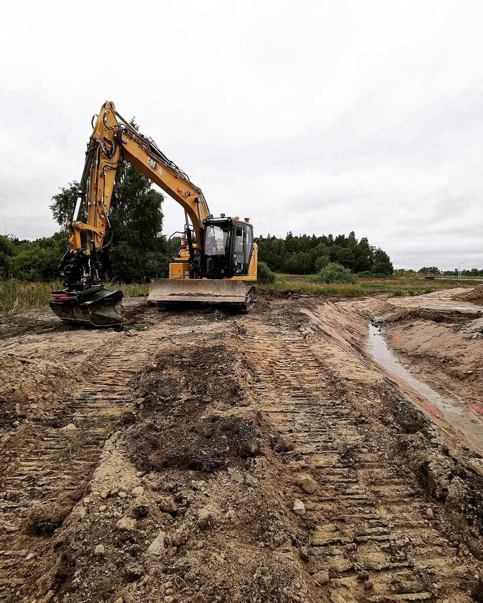 Grävmaskin i arbete med markberedning och dräneringsschakt på landsbygden i Uppsala