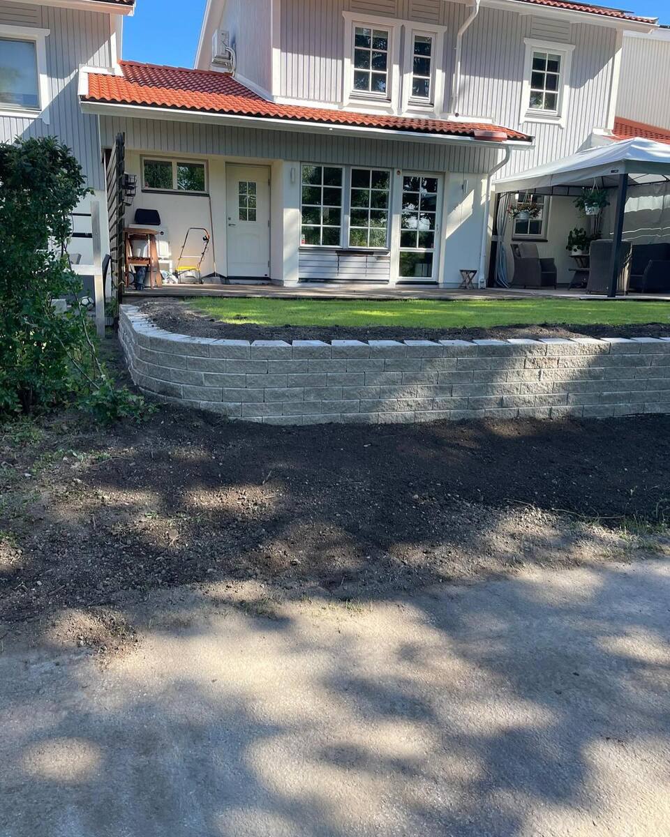 Finplanering av tomt med stödmur och gräsmatta vid radhus i Uppsala