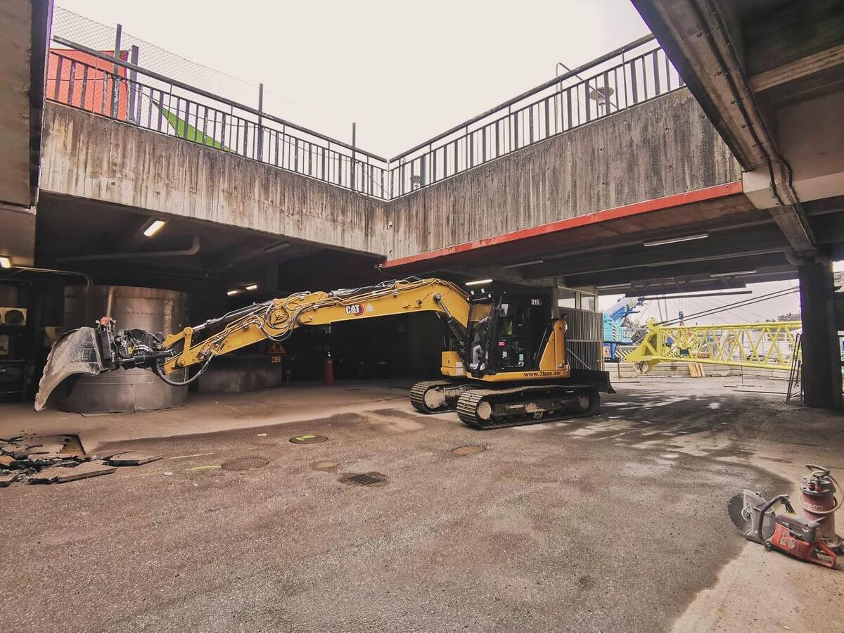 Vägarbete med grävmaskin under bro – anläggningsarbete i Stockholm