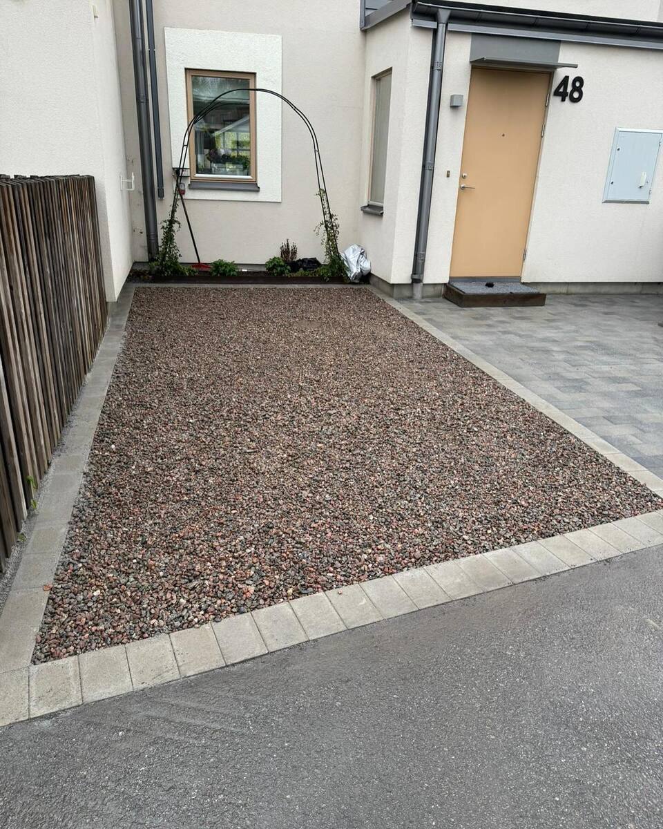 Grusad parkeringsplats eller uppfart med kantsten framför radhus – nyanlagd infart