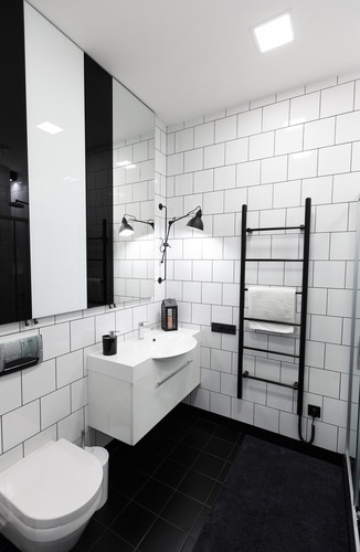 Modern badrumsrenovering i Borlänge med svartvit kakelvägg och elektrisk handdukstork
