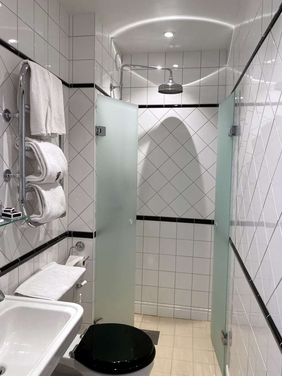Modern badrumsrenovering med vitkakel och dusch med frostat glas