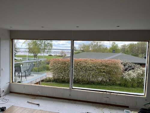 Stort glasparti med fönster sett från insidan av ett rum