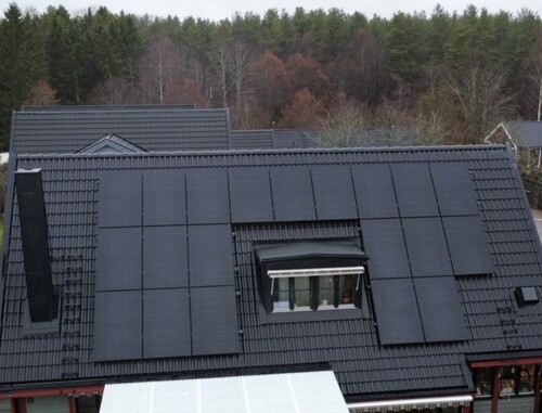 Svart tak med integrerade solpaneler på villa med takpannor