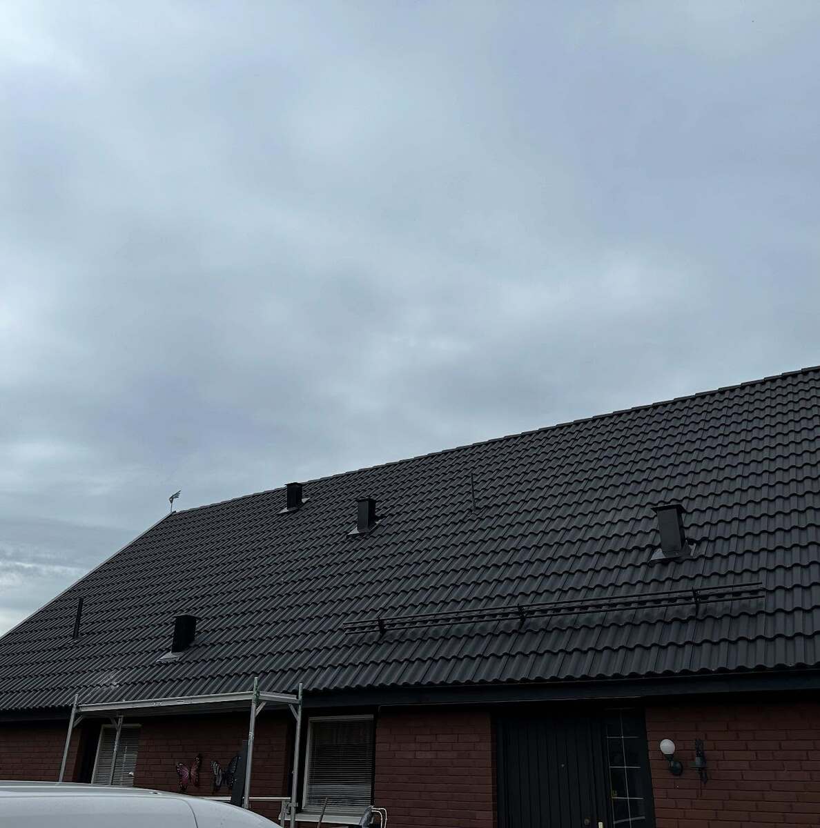 Enplans tegelhus i Örebro med nytt svart tak och flera takkupor, fotat från sidan.