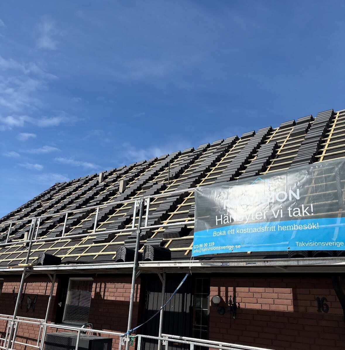 Takrenovering pågår på tegelvilla i Örebro – byggställningar och Takvision-skylt synliga under blå himmel.