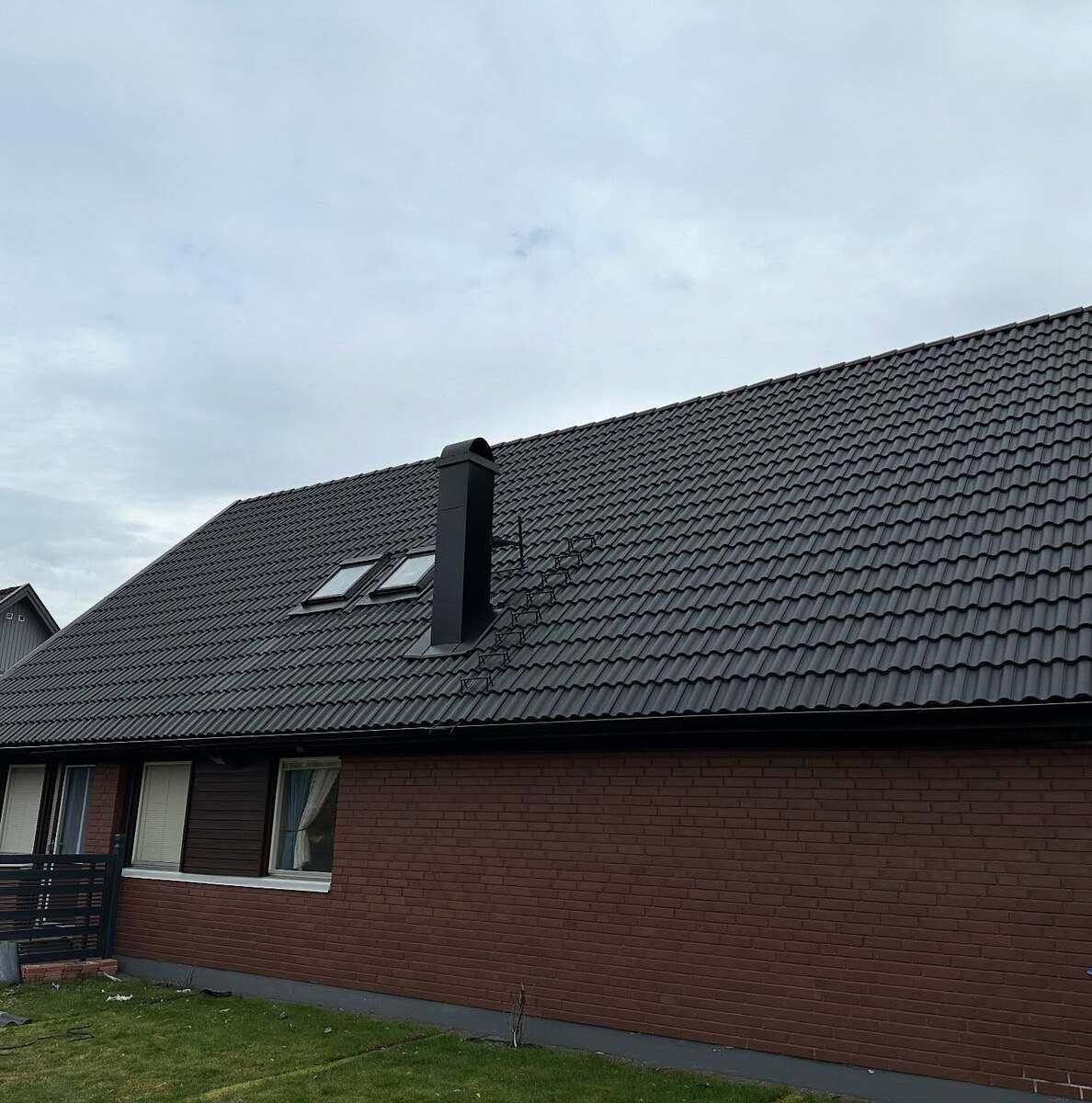 Nyrenoverat tak med svarta takpannor och takfönster på en enplans tegelvilla i Örebro.