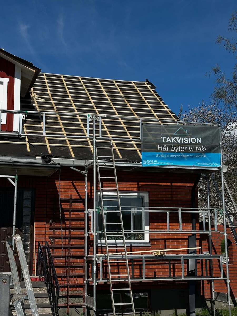 Takbyte på tegelhus i Örebro med synlig underlagspapp och läktning, byggställning uppsatt och Takvision-skylt monterad.