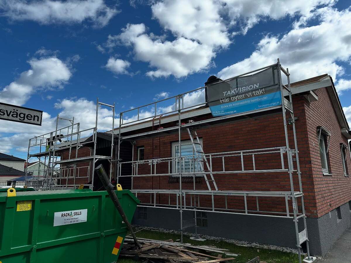 Takbyte pågår på tegelhus i Örebro – byggställningar och skylt från Takvision Sverige synliga, blå himmel i bakgrunden.
